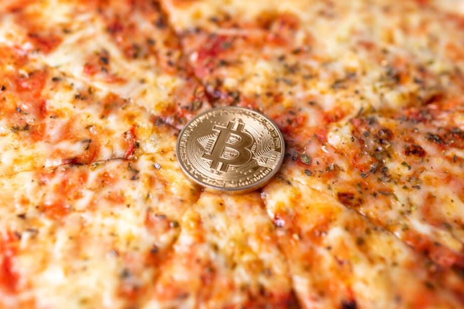 eine bitcoin münze auf einer pizza margaritha